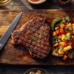 Gegrilltes Steak mit buntem Gemüse auf Holzbrett.