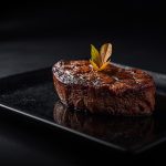 Gegrilltes Steak auf schwarzer Platte mit Garnitur