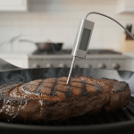 Rindersteak brät in Pfanne, Thermometer sichtbar.