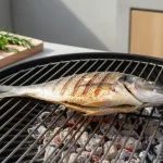 Gegrillter Fisch auf dem Grillrost mit Zitronen.