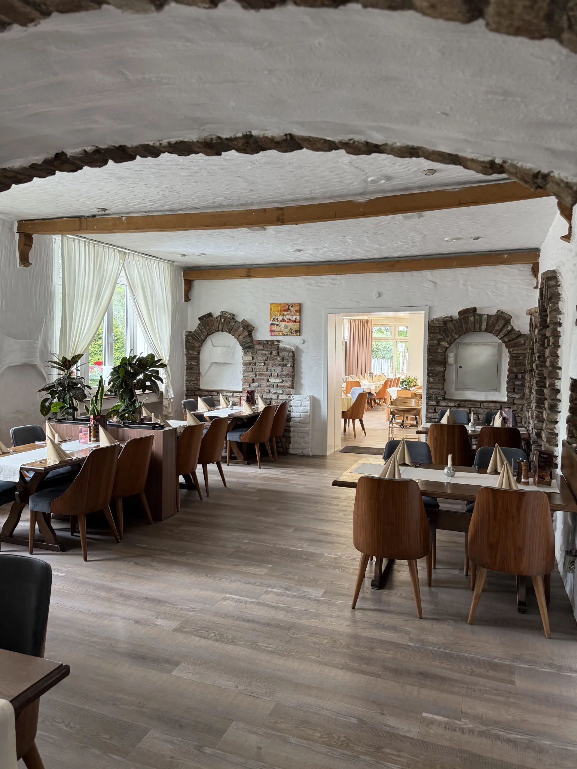 Heller Speisesaal mit Holzbalken und Steinbögen.