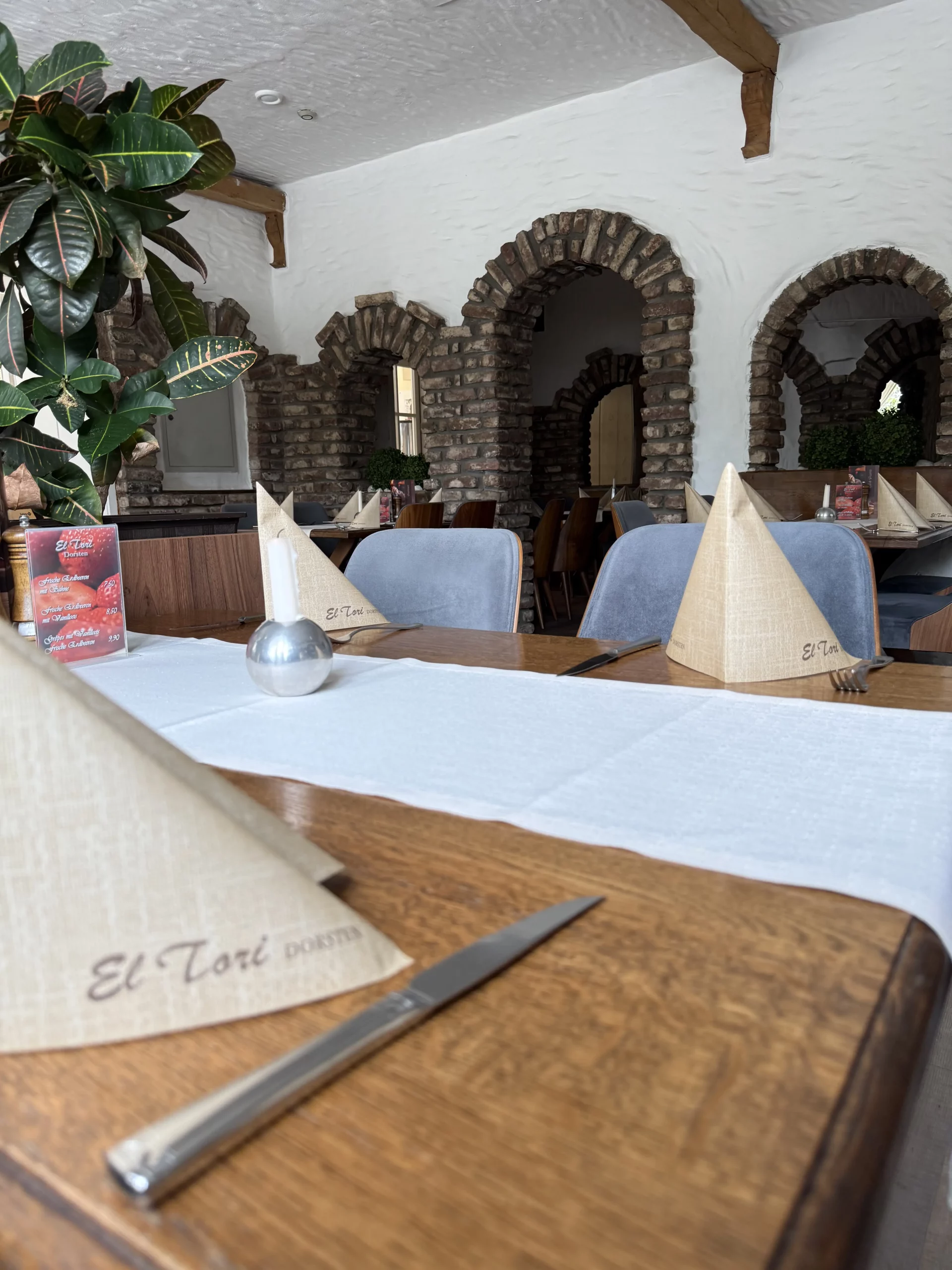 Restaurant mit Steinbogen-Architektur, weißen Wänden und Tischen.