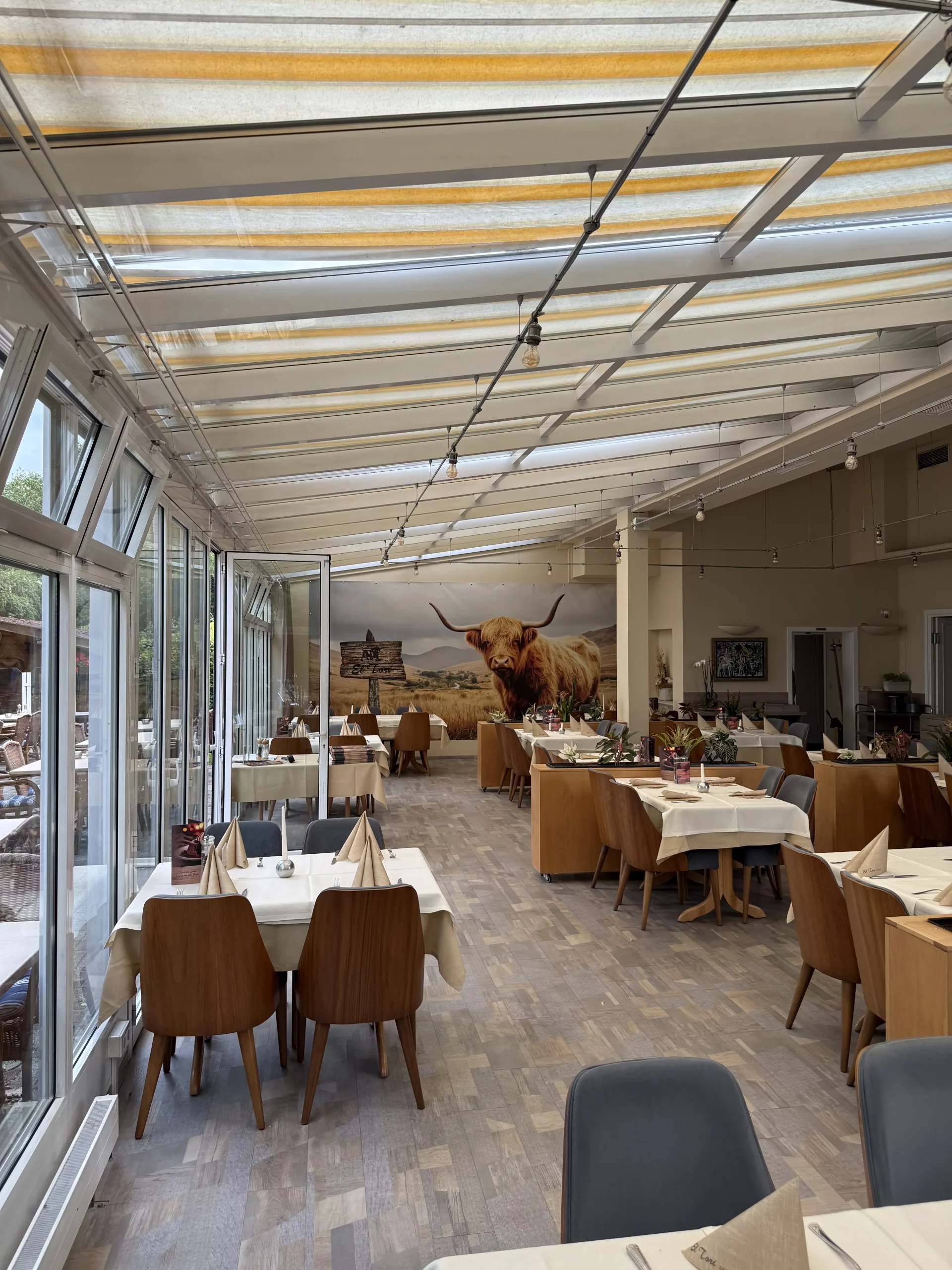 Heller Restaurant-Innenraum mit Glasdach und Kuhbild