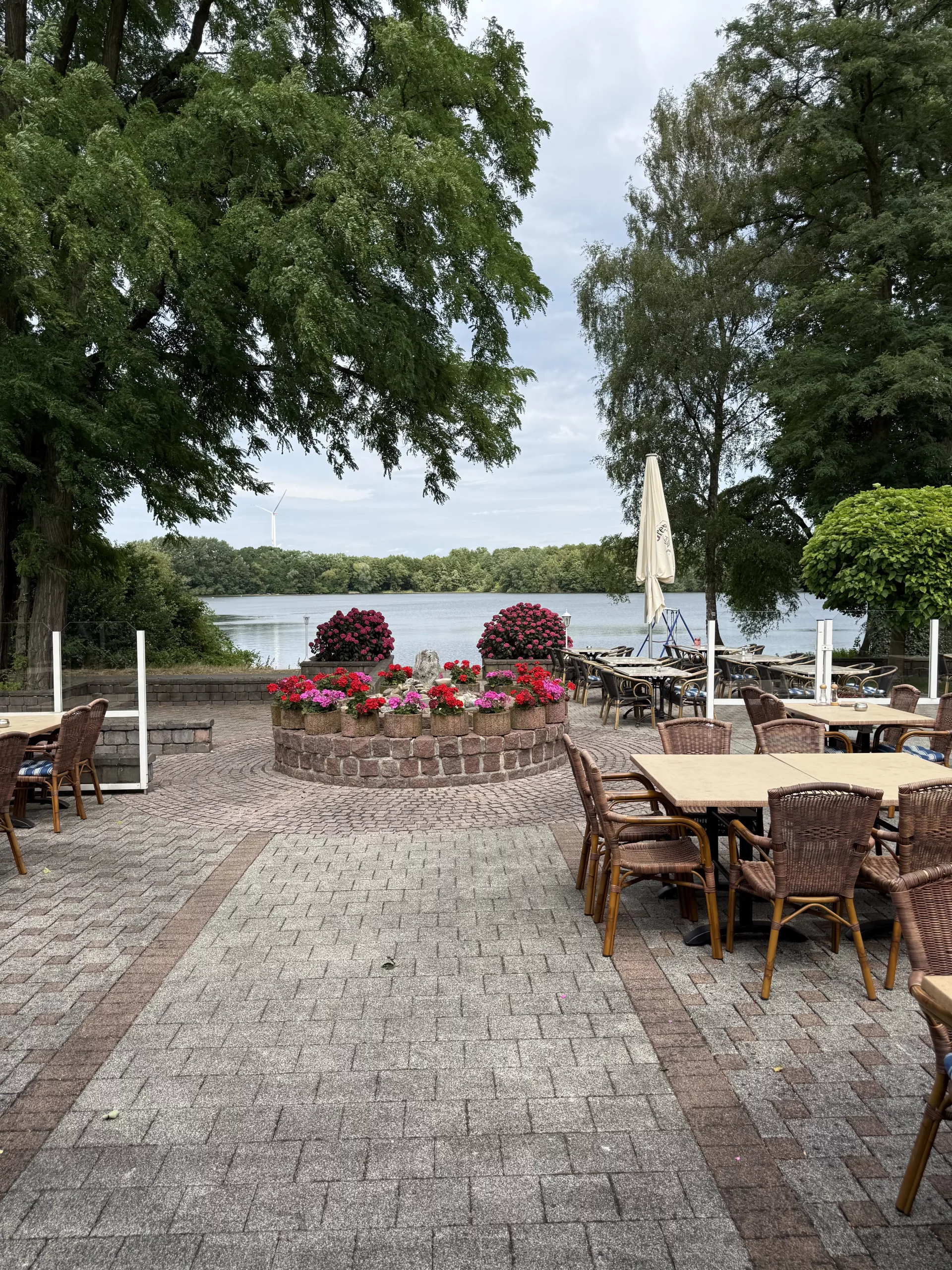 Gartencafé am See mit Blumen, Tischen und Stühlen