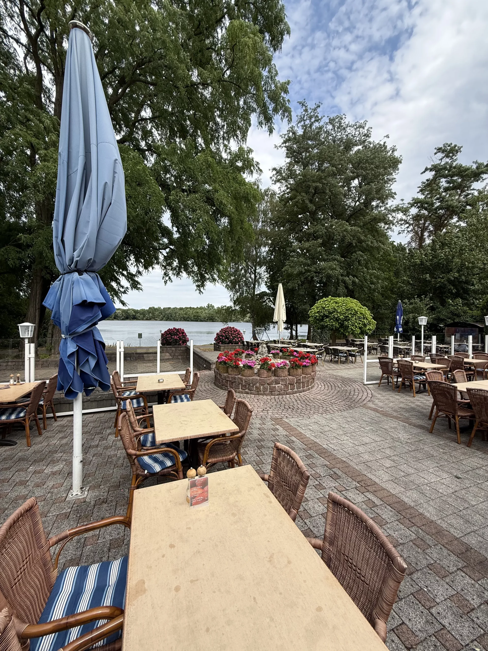 Außenbereich am See mit geschlossenen blauen Sonnenschirmen.