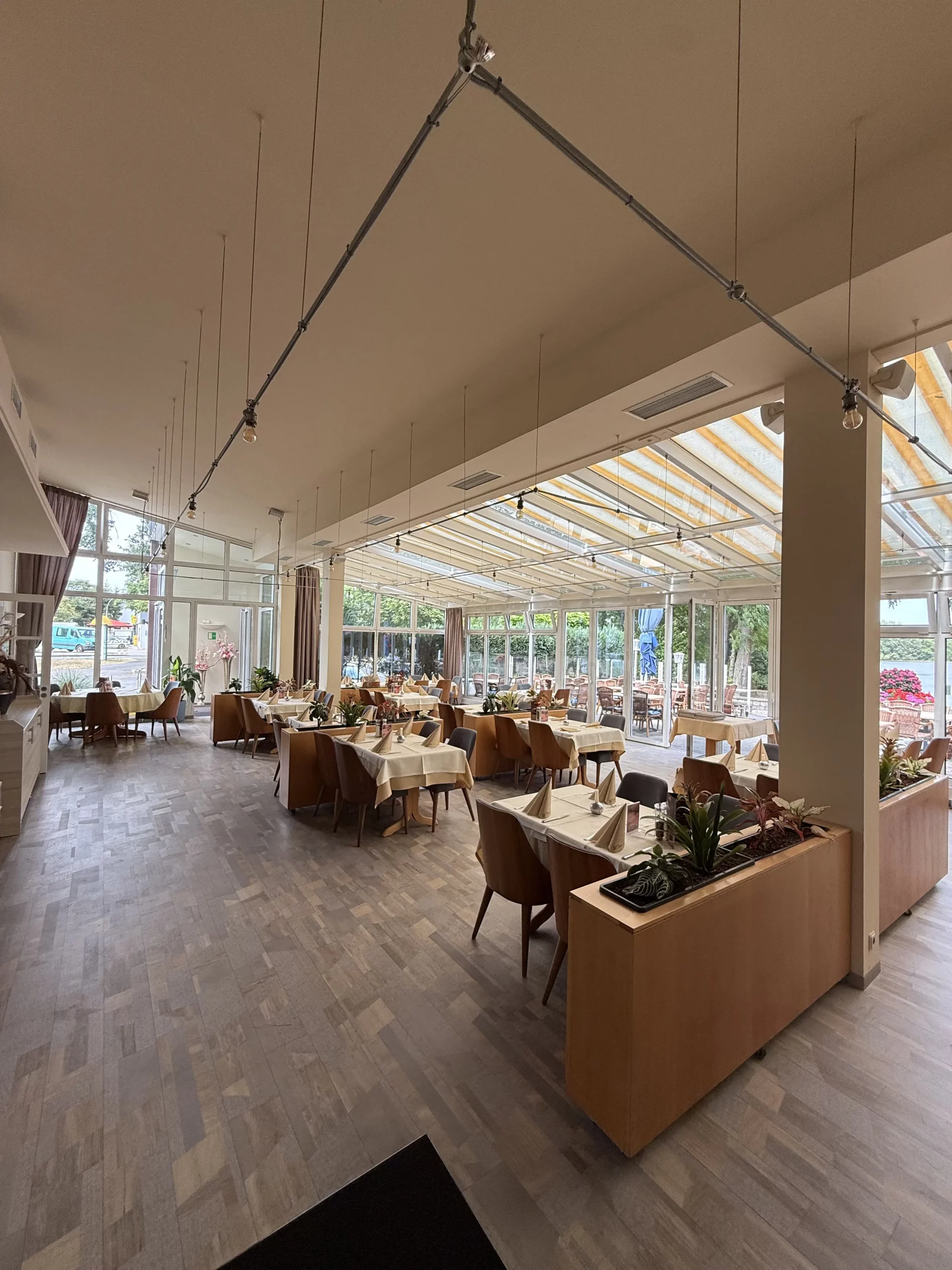 Helles Restaurantinterieur mit gedeckten Tischen und Beleuchtung.